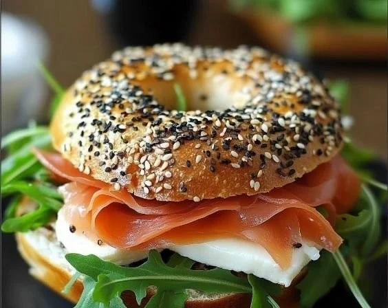 Leckerer Bagel mit Räucherlachs, Frischkäse und Rucola auf einem Teller