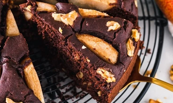 Saftiger veganer Birnen-Kuchen auf einem Teller, dekoriert mit frischen Birnen.